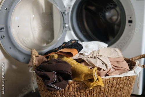 Washing concept. laundry close up. A washing machine and a pile of dirty clothes in basket. A pile of dirty clothes in a basket in front of the washing machine