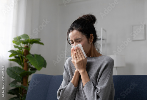 The young woman sat on the sofa in the living room, clutching her chest in obvious discomfort, possibly indicating heartburn. She also had a cough, sore throat, and runny nose.