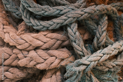 Tangled heavy ship lines and old fibrous hawsers fill the frame in a detailed seafaring still life, evoking dock work, anchoring, endurance and coastal heritage.