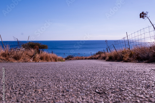 Low angle view along coastal road ending at the blue sea