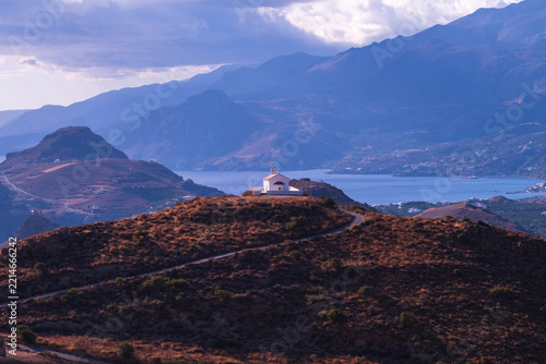 Whitewashed chapel on a coastal hilltop at sunset