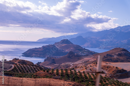 Rugged Mediterranean coastline with olive groves and mountains