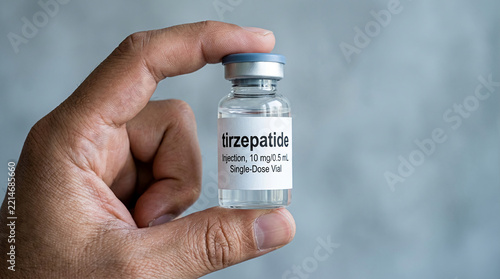 Close-up of a hand holding a single-dose vial of tirzepatide injection, representing medical treatment and pharmaceutical innovation