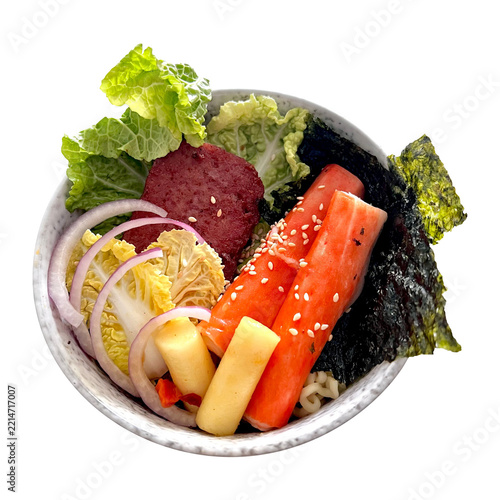 Korean Budae Jjigae Ingredients in a Bowl with Spam, Rice Cakes, Crab Sticks, Nappa Cabbage, Red Onion, and Nori