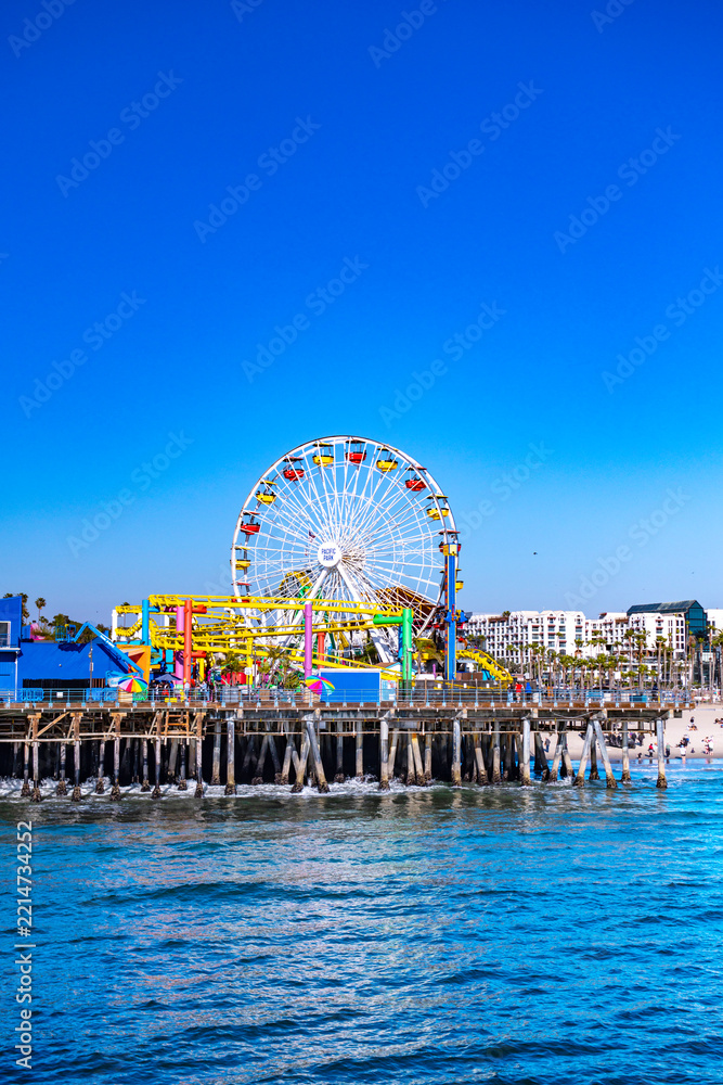 Fototapeta premium Santa Monica beachfront architecture under blue skies. White buildings along Santa Monica oceanfront. Santa Monica coastal buildings behind the beach. Beachfront cityscape near Santa Monica Pacific