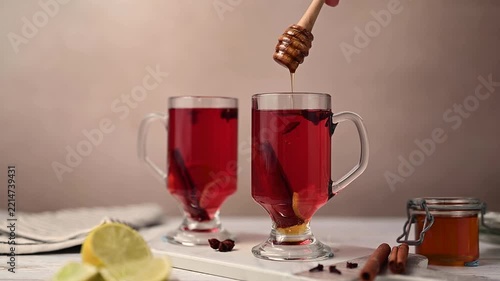 Adding honey to Spiced Tea with Cinnamon, Star Anise and Lemon, Cozy autumn, winter glass cup of tea