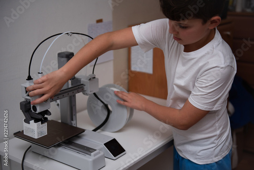 Curious boy using a modern 3D printer at home.