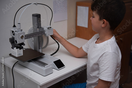 Curious boy using a modern 3D printer at home.