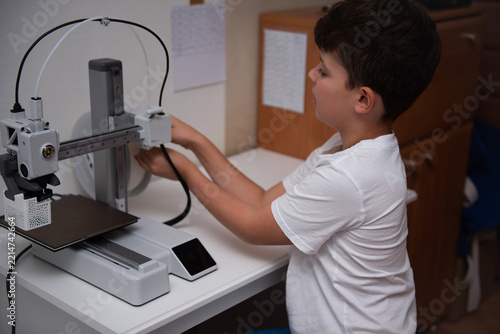 Curious boy using a modern 3D printer at home.