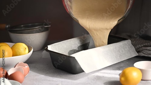 Pouring lemon cake batter into a loaf pan, home baking concept