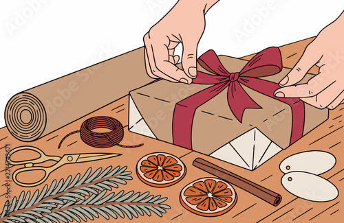 Wrapping presents, hands tying a ribbon on a kraft paper gift