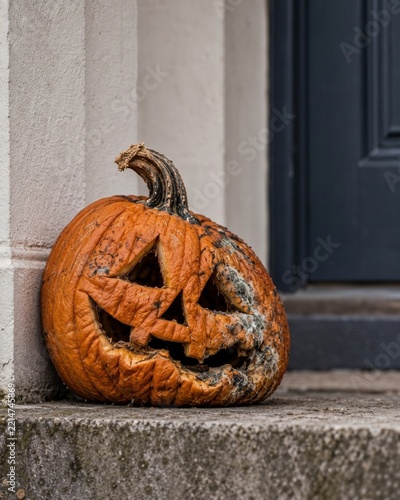 Rotting Halloween jack o lantern pumpkin on doorstep