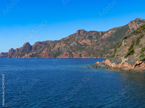 Panoramic view of dramatic red mountain coastline over blue Mediterranean Corsica