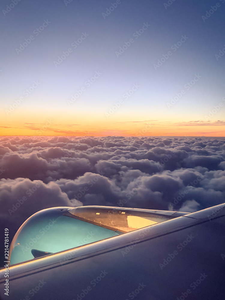Fototapeta premium Airplane wing and engine against breathtaking sunset clouds and gradient sky, aerial travel and freedom concept