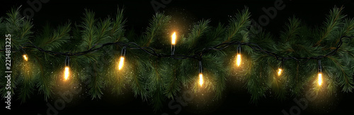 Dense fir garland with warm candle like lights on black background