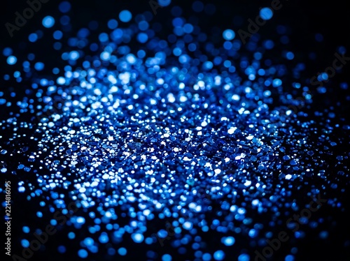 Abstract background featuring vibrant blue glitter particles with soft bokeh effects and a dark atmospheric blurred surface