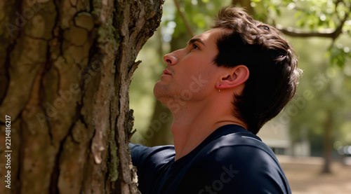 Candid shot from behind a tree, voyeuristic perspective, he is stretching his neck, momentarily pausing from work.
