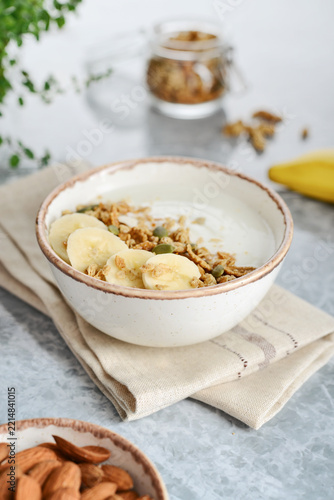 Greek yogurt with muesli and sliced banana in a bowl on a marble countertop