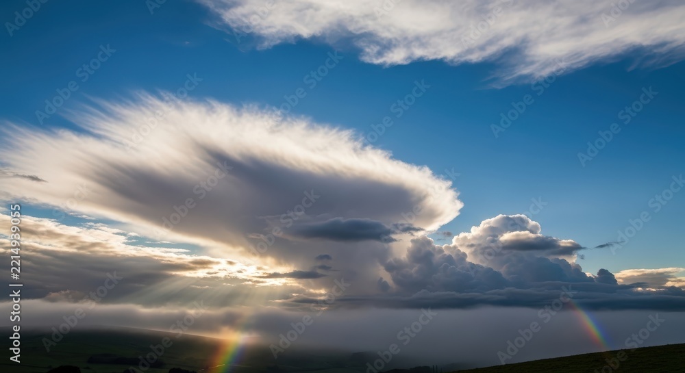 Fototapeta premium Dramatic sunset sky with lenticular clouds and a faint rainbow arc
