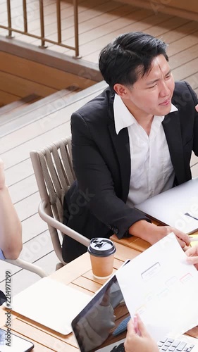 Asian Business Team Discussing Financial Reports During Outdoor Meeting