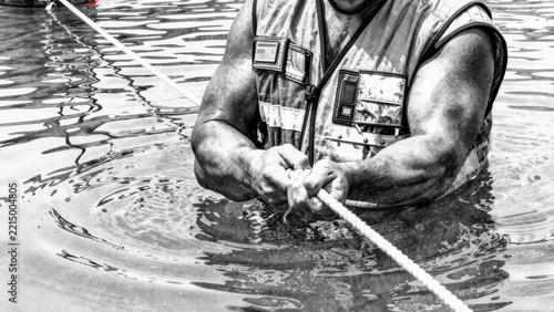 Strong Man Pulling Rope in Water in Safety Vest During Rescue Effort