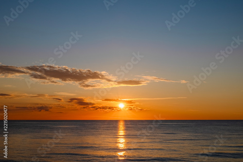 The setting sun over the calm sea, reflected in the water
