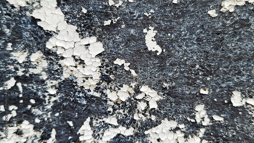 Peeling and cracked white paint on dark rough surface texture photo