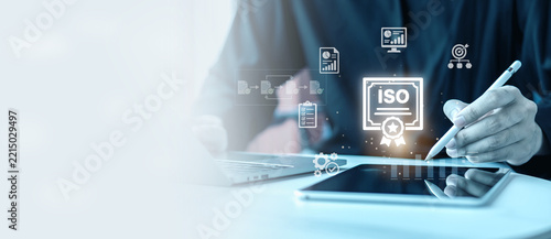 ISO certification quality management standard concept banner. Businessman with stylus pen on tablet with virtual ISO certificate badge, workflow and checklist icons with copy space.