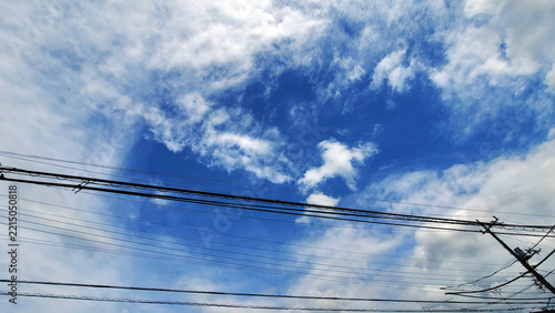 Power lines and utility pole with blue sky and white clouds background photo