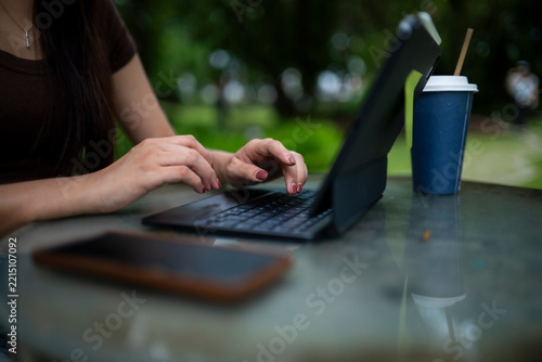 Person Working Outdoors with Laptop, Coffee Cup, and Phone on Table