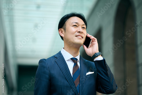 笑顔で電話をする30代男性ビジネスマン