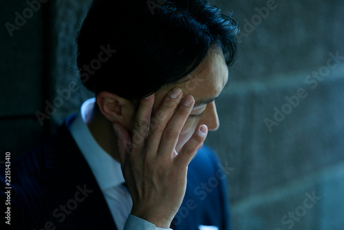 顔に手を当ててうつむく男性ビジネスマン
