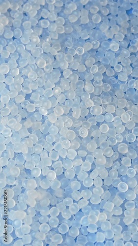 Polyethylene granules rotate as fresh pellets fall from above for medical and plastic production.