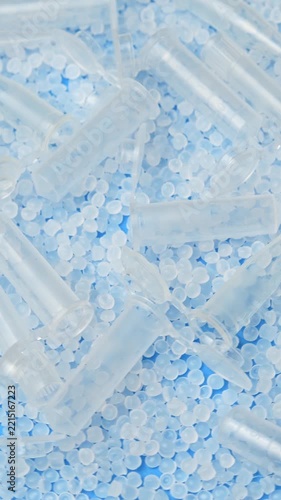 Low angle macro shows clear microtubes and polymer pellets rotating for healthcare manufacturing.