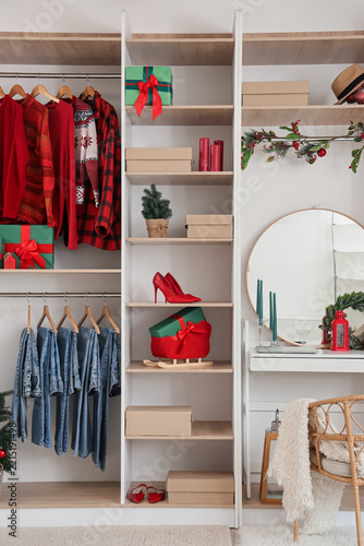 Modern wardrobe with stylish Christmas clothes and gift boxes