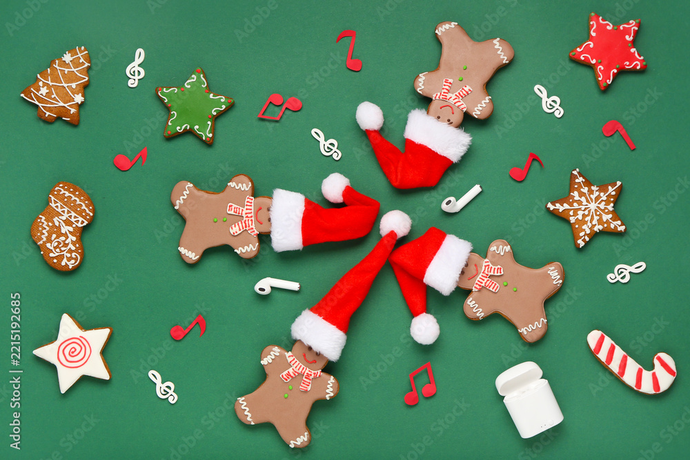Naklejka premium Composition with Christmas cookies in Santa hats, earphones and note signs on green background