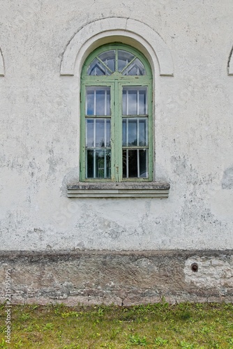 Beautiful, weathered arched window set against a rustic stucco building facade, Estonia, Europe.