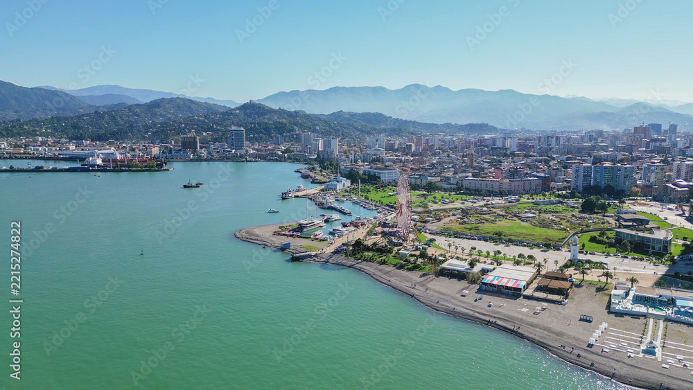 Obraz premium Aerial view of Batumi beach and embankment with green mountains background along Black Sea coast in Adjara Georgia during clear sunny summer day