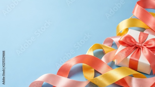 White birthday gift with a coral satin bow and flowing ribbons on a blue back...