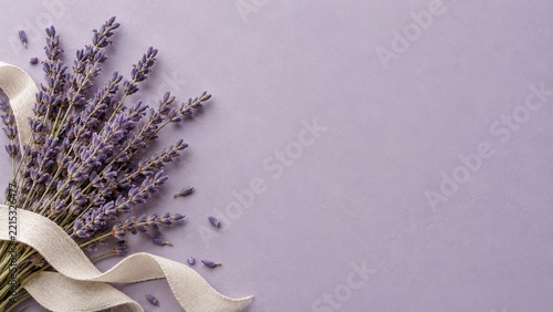 Lavender stems with an ivory linen ribbon on a pale purple textured surface