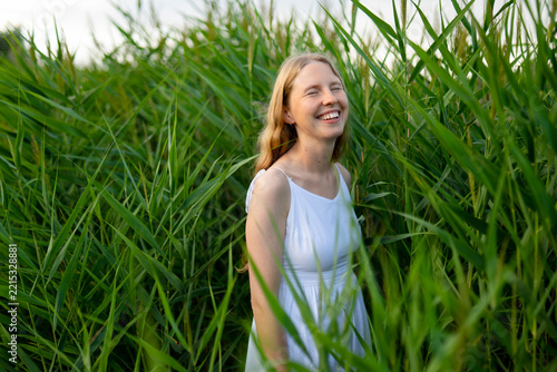 A radiant young woman enjoys summer nature in tall green reeds