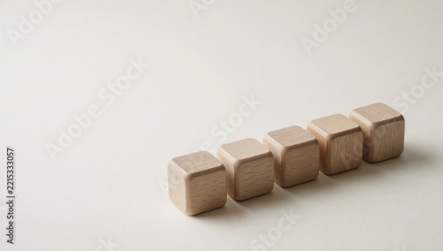 Row of five plain wooden blocks on a cream surface