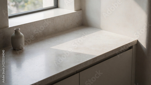 Sunlit stone kitchen counter with a small vase and window