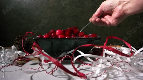 Hand stirring red ripe cranberries in a bowl for Christmas