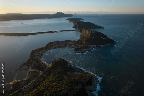 Aerial view of Voidokilia Beach with its distinctive semicircular shape, surrounded by rocky hills and the Ionian Sea in Greece.