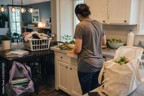 Woman managing multiple household tasks in kitchen illustrating invisible mental load and everyday responsibilities