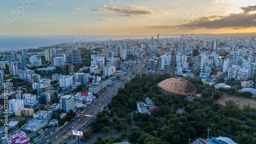 Aerial view of the Santo Domingo skyline featuring the Palacio de los Deportes dome, lush parkland, and urban streets at sunset in Santo Domingo, Distrito Nacional, Dominican Republic.