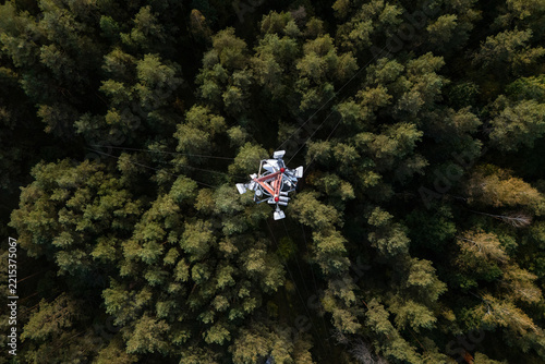 Aerial view of a telecommunications tower rising above a dense pine forest in Varena, Alytus County, Lithuania.
