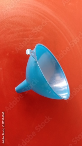 Open view of a blue plastic funnel showing inner cone on red background