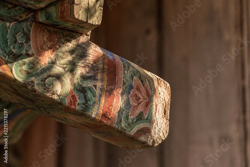 Weathered wooden temple rafter with faded dancheong patterns, Korean heritage concept